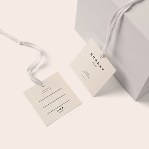 May include: Two beige square gift tags with string attached. The tag on the left says "Solstice Candle Co." and has three lines for writing. The tag on the right says "SUNDAY NO. 21 100% NATURAL HANDMADE".