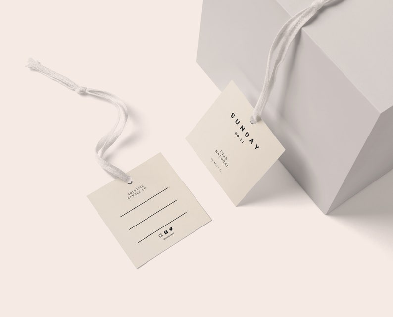 May include: Two beige square gift tags with string attached. The tag on the left says "Solstice Candle Co." and has three lines for writing. The tag on the right says "SUNDAY NO. 21 100% NATURAL HANDMADE".