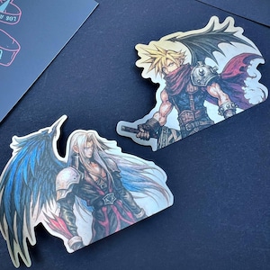 May include: Two stickers featuring Final Fantasy characters. One depicts a blonde-haired character with a red scarf and black wing. The other shows a long-haired character with a silver wing. Both stickers have detailed artwork and are on a dark background.