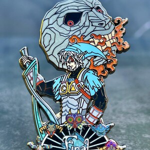 May include: A detailed enamel pin featuring a character with a blue hat and sword, set against a background of a skull and flames. The pin has a black, blue, white, and orange color scheme, with the word "Final" at the bottom.