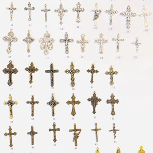 May include: A collection of 52 silver, bronze, and gold cross charms. The charms are arranged in rows on a white background. Each charm is numbered from 1 to 52.