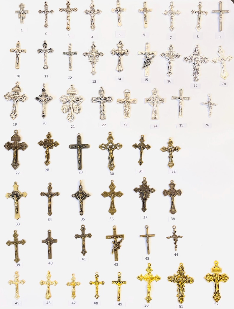May include: A collection of 52 silver, bronze, and gold cross charms. The charms are arranged in rows on a white background. Each charm is numbered from 1 to 52.