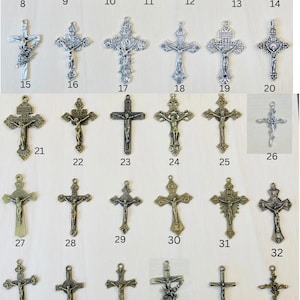 Może przedstawiać: Kolekcja 47 srebrnych i złotych metalowych krucyfiks&oacute;w o r&oacute;żnych wzorach. Krucyfiksy są ułożone w rzędach na jasnym drewnianym tle.
