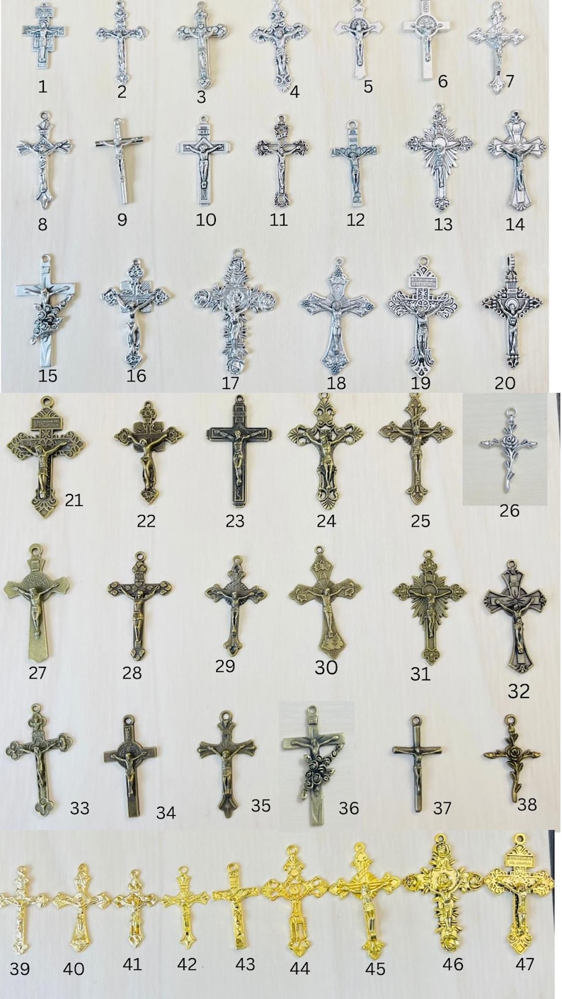 Może przedstawiać: Kolekcja 47 srebrnych i złotych metalowych krucyfiks&oacute;w o r&oacute;żnych wzorach. Krucyfiksy są ułożone w rzędach na jasnym drewnianym tle.