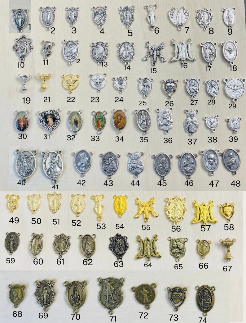 May include: A collection of 74 silver and gold religious medallions, charms, and pendants. The medallions feature various religious figures and symbols, including the Virgin Mary, Jesus Christ, and the Holy Spirit. The medallions are arranged in rows and columns on a wooden surface.