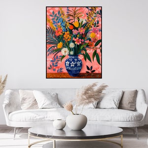 May include: A blue and white porcelain vase filled with a colorful bouquet of flowers, including pink, red, yellow, and orange blooms. The vase is sitting on a wooden table against a pink background.