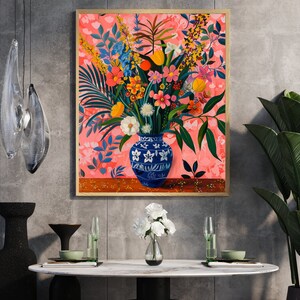 May include: A framed painting of a colorful floral arrangement in a blue and white ceramic vase. The flowers are arranged in a vase on a wooden table. The background is a pink and white floral pattern.