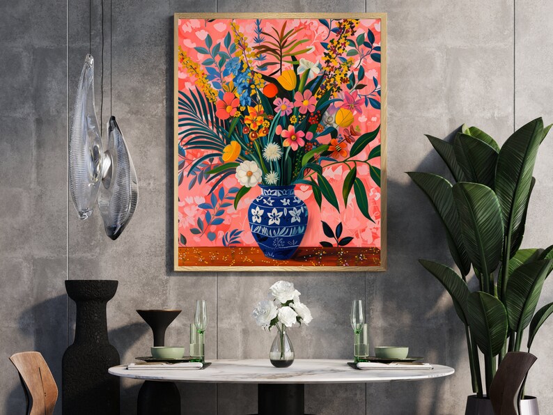 May include: A framed painting of a colorful floral arrangement in a blue and white ceramic vase. The flowers are arranged in a vase on a wooden table. The background is a pink and white floral pattern.