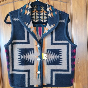 Könnte beinhalten: Eine schwarze Wollweste mit einem geometrischen Muster in Braun-, Orange-, Blaugrün- und Rottönen. Die Weste hat einen Schalkragen und einen Knopfverschluss.