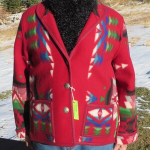 May include: A red wool jacket with a geometric pattern in shades of blue, green, and white. The jacket has a shawl collar, two pockets, and a button closure.
