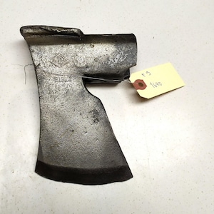 Op de afbeelding: Een vintage bijlkop met een ruitvormig logo en de tekst "F.G. 1640" op een geel label.