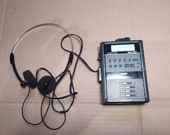 May include: A black cassette player with a silver headset. The player has a digital tuner and a Toshiba logo. The player has a bass boost button and a few buttons for tuning.