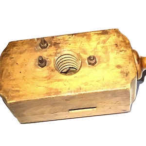 Op de afbeelding: Een houten gereedschap met twee knoppen aan beide uiteinden en een centraal gat met een schroefdraad van metaal. Het gereedschap is gemaakt van lichtbruin hout en heeft een versleten, antieke uitstraling.