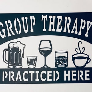 May include: Black metal sign with white text that reads "Group Therapy Practiced Here". The sign features a beer mug, a wine glass, a shot glass, a glass of whiskey with ice, and a coffee cup.