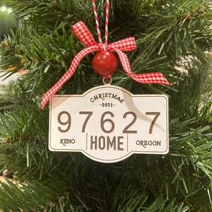 May include: A white wooden Christmas ornament with red and white checkered ribbon, a red ball, and the text "Christmas 2021" and "97627 KENO HOME OREGON".