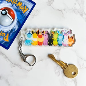 Clear acrylic Eeveelution keychain next to a Pokemon card and a key
