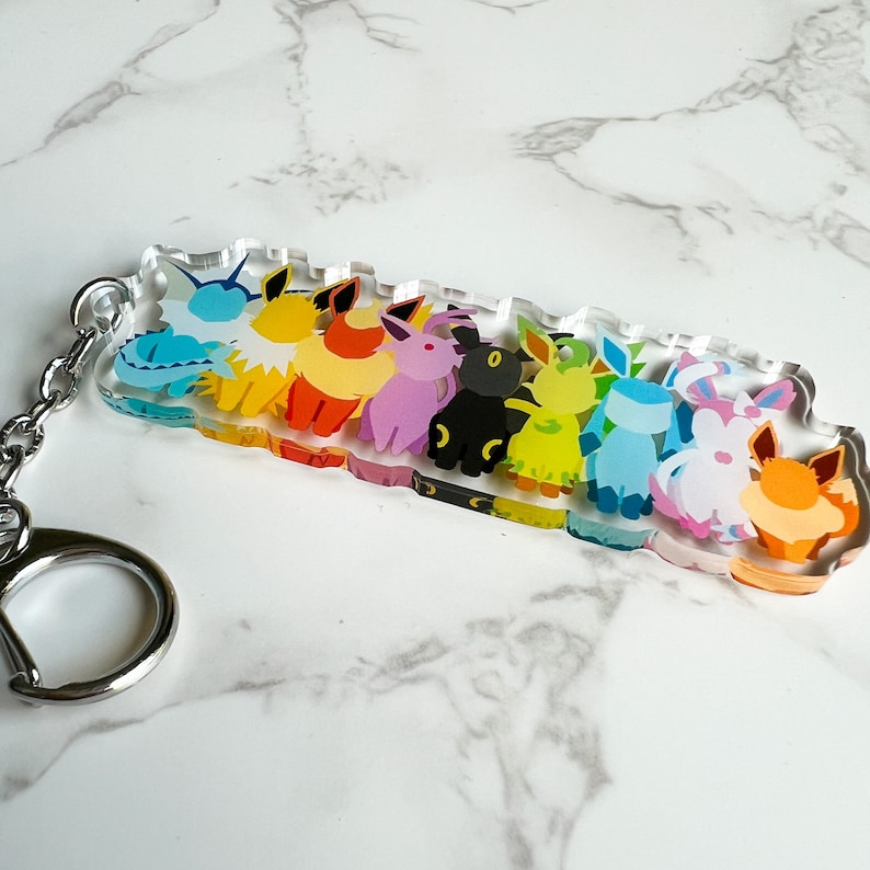 Close up of the Eeveelutions keychain to show the vibrant colors, metal clip on keyring, and durable high quality acrylic material.