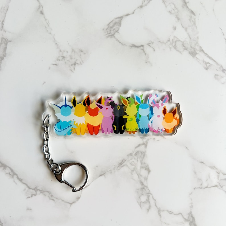 Eevee Evolutions clear acrylic keychain featuring all the Eeveelutions: Flareon, Jolteon, Vaporeon, Umbreon, Espeon, Leafeon, Glaceon, and Sylveon with a metal clip on attachment.