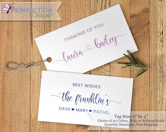 May include: Two white gift tags with calligraphy text. The top tag says "Thinking of you Laura bailey" in purple script with a pink heart. The bottom tag says "Best Wishes the franklin's DAVE MARY RACHEL" in blue script with a blue heart. The tags are 2 inches by 4 inches.