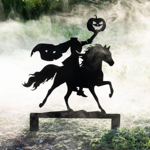 May include: Black metal silhouette of the Headless Horseman riding a horse, holding a jack-o'-lantern. The Halloween decoration is set against a backdrop of green foliage and fog, perfect for outdoor display.