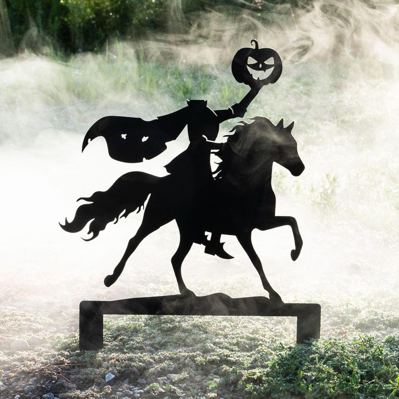 May include: Black metal silhouette of the Headless Horseman riding a horse, holding a jack-o'-lantern. The Halloween decoration is set against a backdrop of green foliage and fog, perfect for outdoor display.