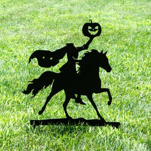 May include: Black metal silhouette of the Headless Horseman riding a horse, holding a jack-o'-lantern. The artwork is set against a backdrop of green grass, evoking a Halloween theme. The horse is in mid-stride.