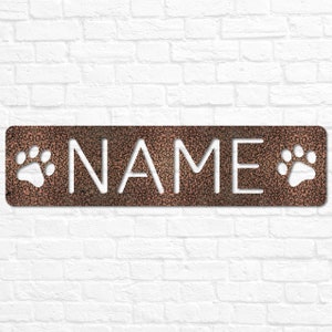 May include: A copper-colored metal sign with the word "NAME" cut out in white. The sign has two white paw prints on either side of the word.