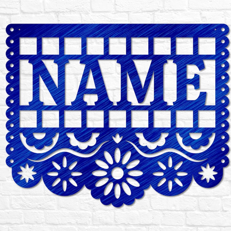May include: A blue metal sign featuring the word "NAME" in a cut-out design. The sign has a decorative scalloped edge and floral and star cutouts. The background is a white brick wall.
