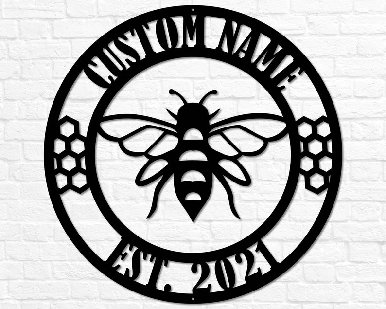 May include: Black metal circle sign with a bee and honeycomb design. The sign says "Custom Name Est. 2021".