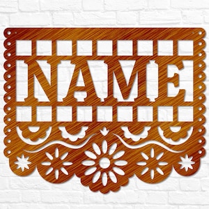 May include: A wooden sign with the word "NAME" cut out. The sign has a scalloped edge and a decorative floral and geometric design. The wood has a warm, natural finish. The sign is designed for display.