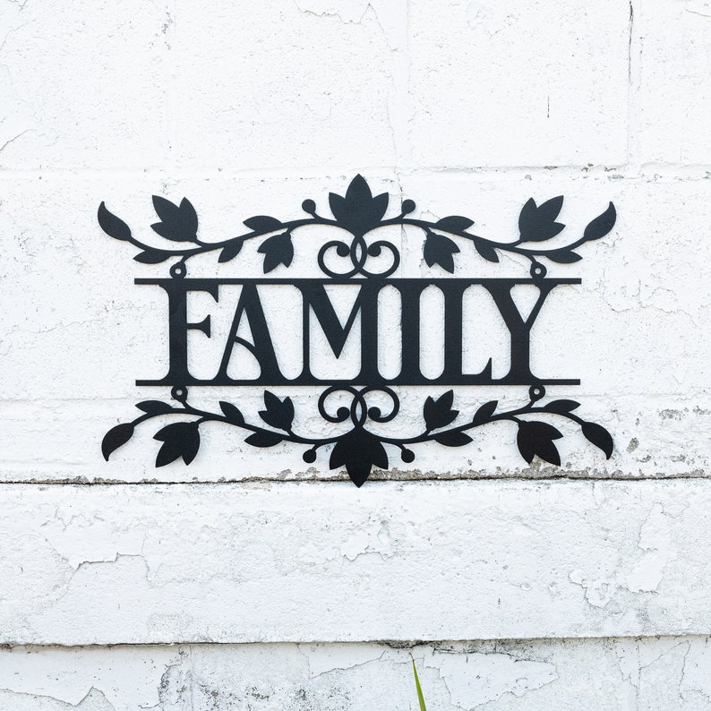 Puede incluir: Decoraci&oacute;n de pared de metal negro con un dise&ntilde;o floral y la palabra "FAMILY" en el centro.