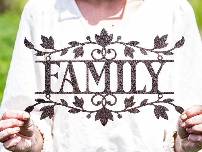 Puede incluir: Un letrero de metal con la palabra "FAMILY" en una fuente decorativa. El letrero est&aacute; decorado con un dise&ntilde;o de vid y hojas.
