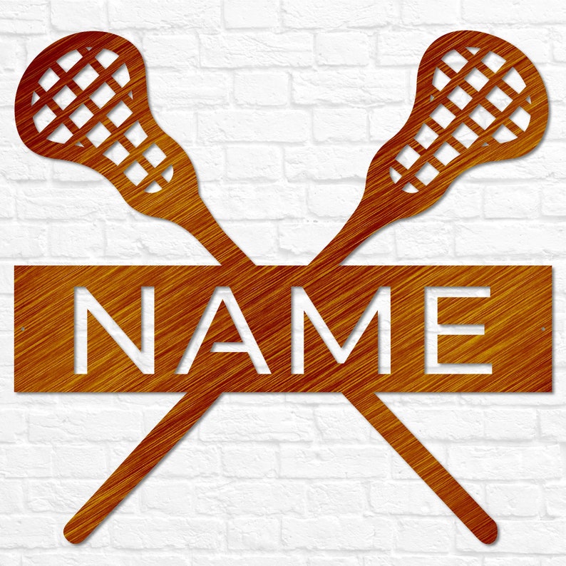 May include: A metal lacrosse stick wall decor with a wooden nameplate. The sticks are crossed and the nameplate is in the center. The nameplate is brown with white lettering. The sticks are orange.