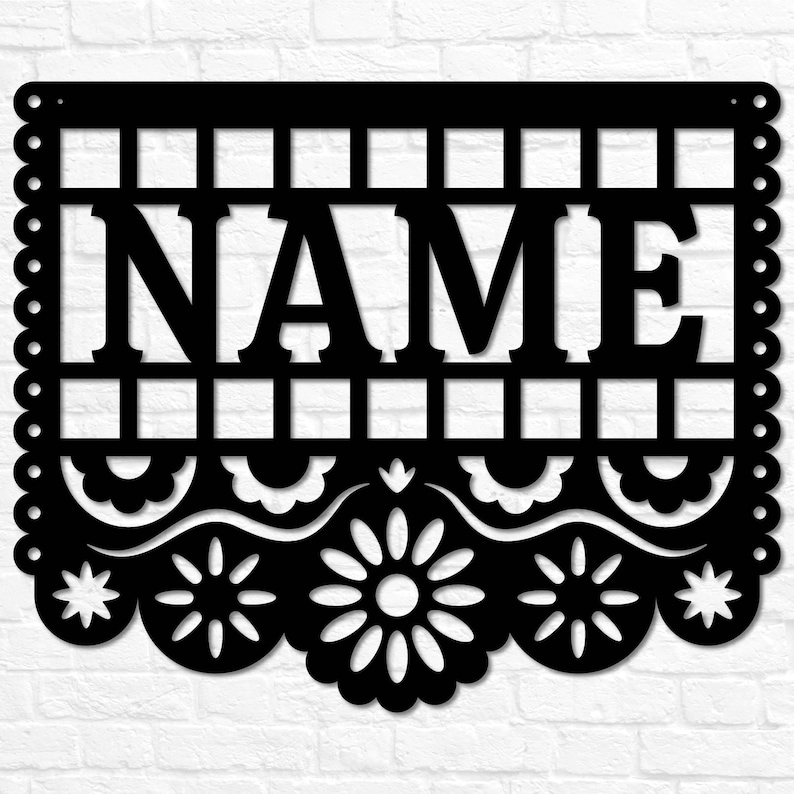 May include: Black metal sign featuring the word "NAME" in capital letters. The sign has a decorative border with scalloped edges and floral cutouts. The background is a white brick wall.