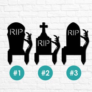 May include: Three black metal Halloween tombstone yard stakes. Each tombstone has the letters "RIP" and a zombie hand reaching out. The stakes are numbered #1, #2, and #3 in teal circles.