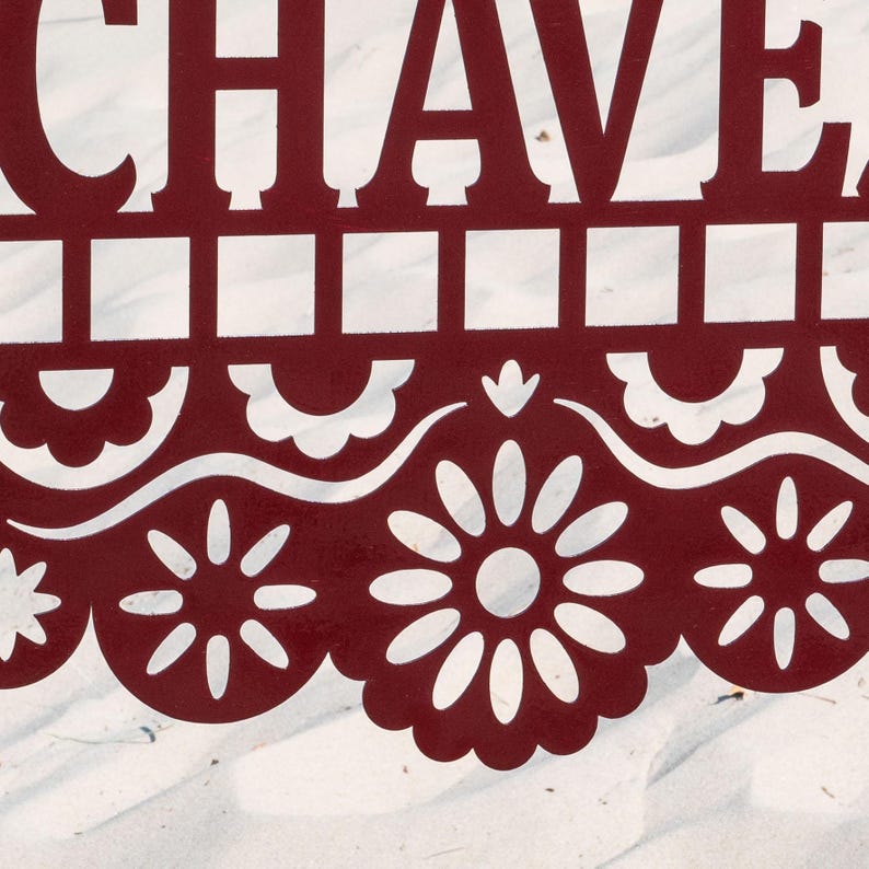 May include: A close-up of a burgundy decorative cutout with the word "CHAVE" at the top. The cutout features a repeating pattern of squares and floral designs. The background is a white, textured surface.