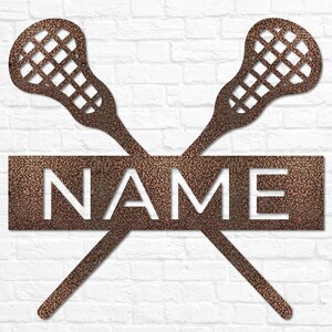 May include: A metal wall decor featuring two crossed lacrosse sticks with a rectangular sign that says "NAME". The sign and sticks are a copper color.