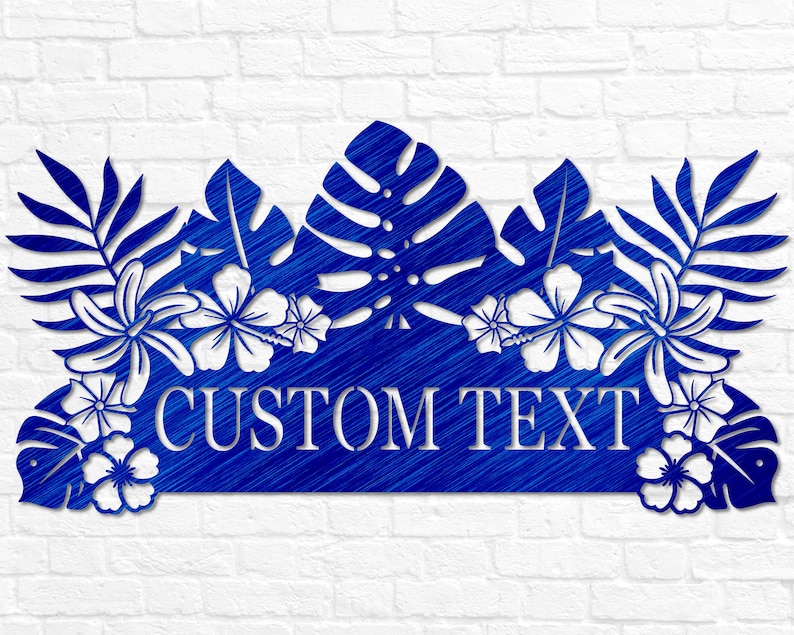 Puede incluir: Arte de pared de metal azul con hojas y flores tropicales y una pancarta de texto personalizable que dice "CUSTOM TEXT".