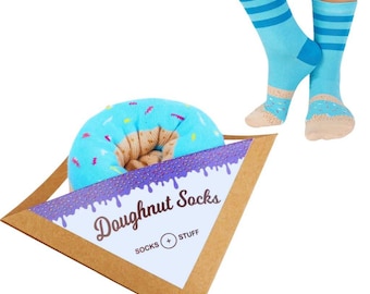 May include: A pair of blue and white striped socks with a donut design. The socks are packaged in a brown triangle-shaped box with the words "Doughnut Socks" and "Socks + Stuff" printed on it.