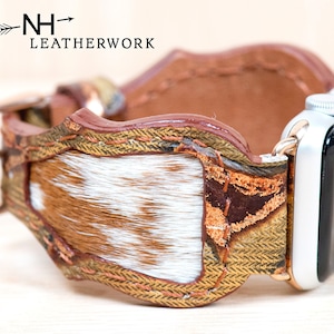 May include: A brown and white leather watch band with a decorative design. The band features a cowhide pattern and a metal buckle. The watch face is silver and black. The brand name "NH Leatherwork" is visible.