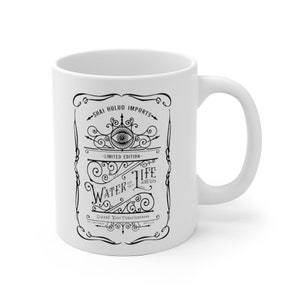 May include: White ceramic mug with a black and white graphic design featuring an eye, ornate swirls, and the text "Shai Hulud Imports - Limited Edition - Water of Life - Sacred Elixir - Expand Your Consciousness".