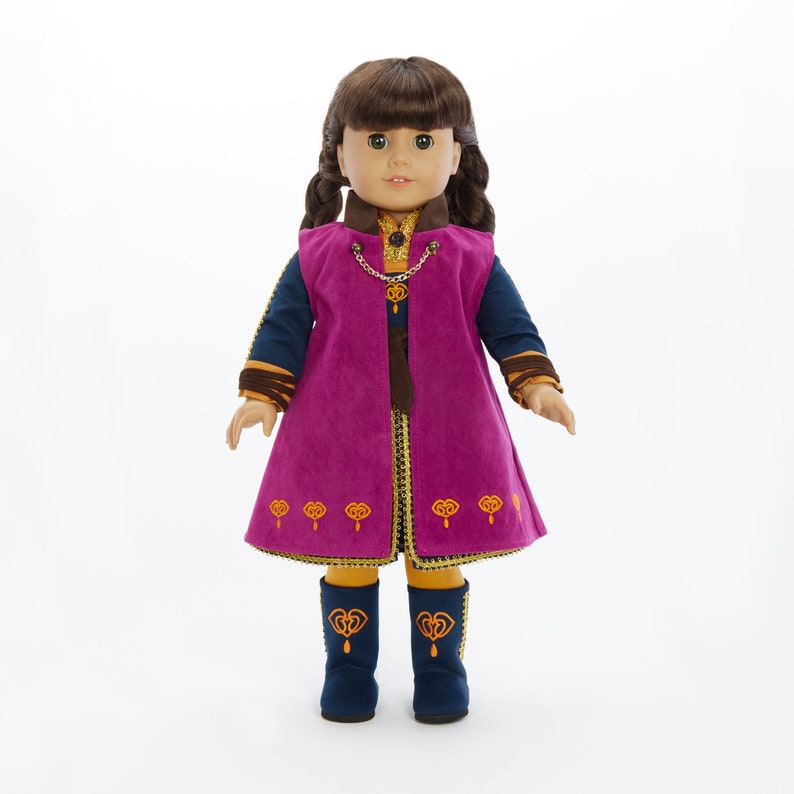 May include: A doll wearing a purple and gold dress with a blue vest and matching boots. The doll has brown hair in braids and blue eyes.
