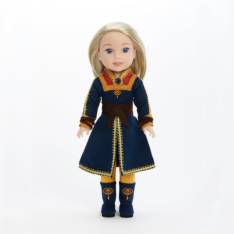 Puede incluir: Una mu&ntilde;eca con un vestido azul y dorado con un cintur&oacute;n marr&oacute;n. La mu&ntilde;eca tiene el pelo rubio y los ojos azules.