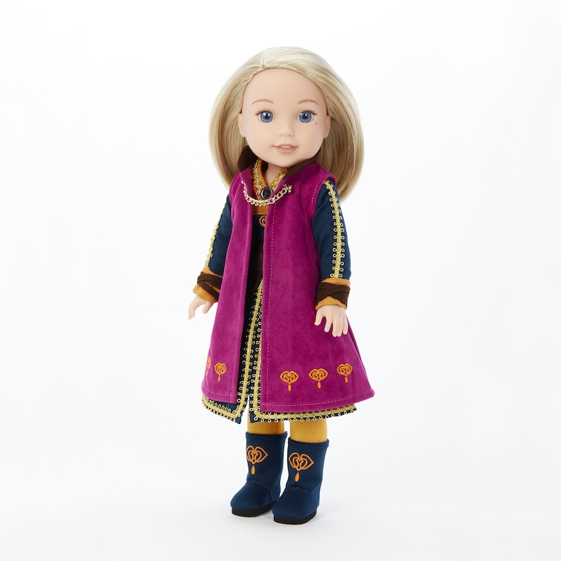 Puede incluir: Una mu&ntilde;eca con un vestido morado y dorado, un chaleco azul y botas a juego. La mu&ntilde;eca tiene el pelo rubio y los ojos azules.