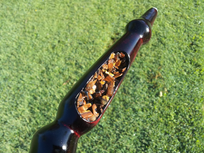 Puede incluir: Una pipa de fumar burdeos oscuro con un tallo largo y curvado. La pipa tiene una cazoleta grande, de forma ovalada, llena de tabaco marr&oacute;n. El fondo es un c&eacute;sped verde borroso.