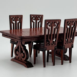 May include: Miniature wooden dining set with a rectangular table and four chairs. The table and chairs are a dark reddish-brown color. The chairs have ornate, carved backs. The table has decorative legs.