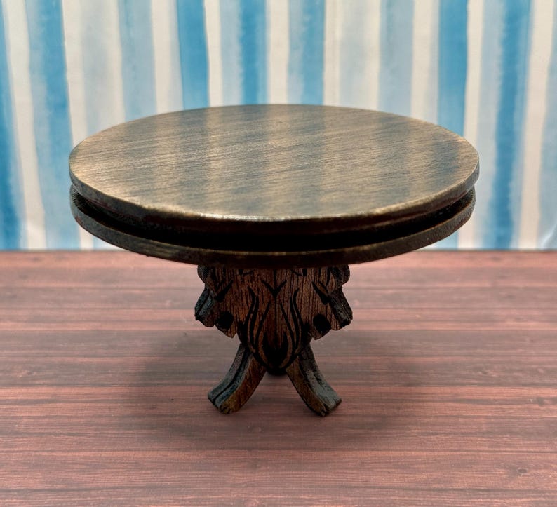 May include: A dark brown wooden table with a round top and a carved base. The table is made of wood and has a rustic look.