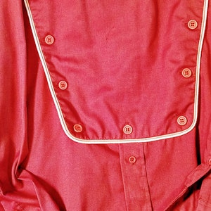May include: A red long-sleeved shirt with a white trim around the collar and a row of buttons down the front.