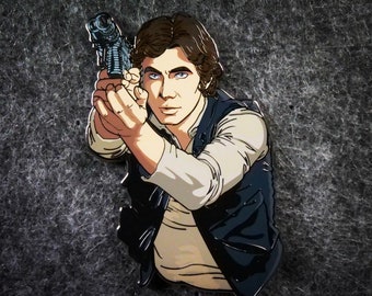 Può includere: Un primo piano di uno spillo smaltato di Han Solo. Lo spillo presenta un'illustrazione dettagliata di Han Solo che tiene un blaster, con un giubbotto nero e una camicia bianca. Lo spillo ha una finitura lucida ed è posizionato su uno sfondo grigio scuro.
