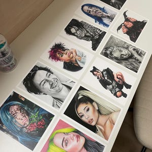 May include: A collection of 10 framed drawings of various celebrities, including Billie Eilish, Harry Styles, and Ariana Grande. The drawings are done in black and white and colored pencil, and they are all framed in simple black frames.